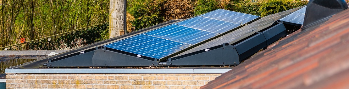 Zonnepanelen op een dak met de tuin van de buren als achtergrond