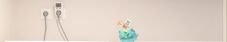 twee stopcontacten en een spaarvarken met geld er in.