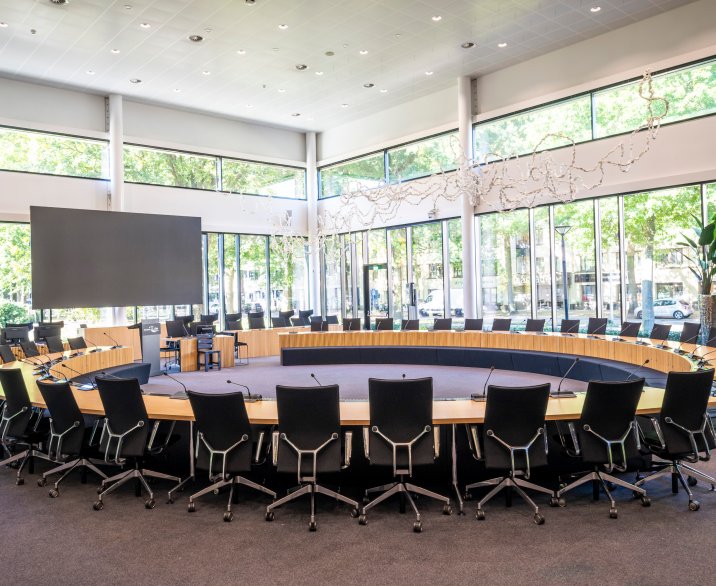 Zaal met stoelen aan een grote ronden tafel